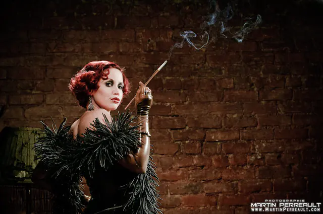 A woman in a feather stole with a cigarette holder, against a brick wall