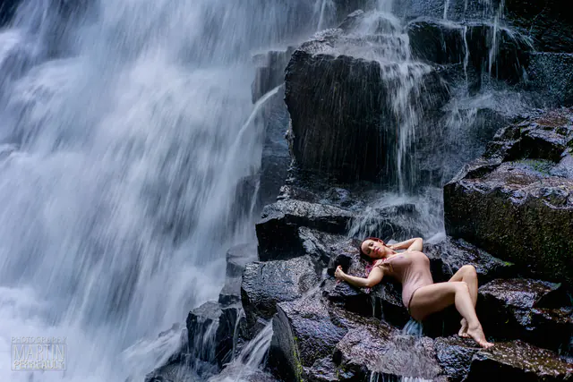 A model lying on the rocks of a waterfall