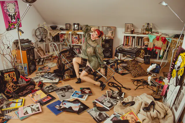 A model in latex lying among the clutter of an attic