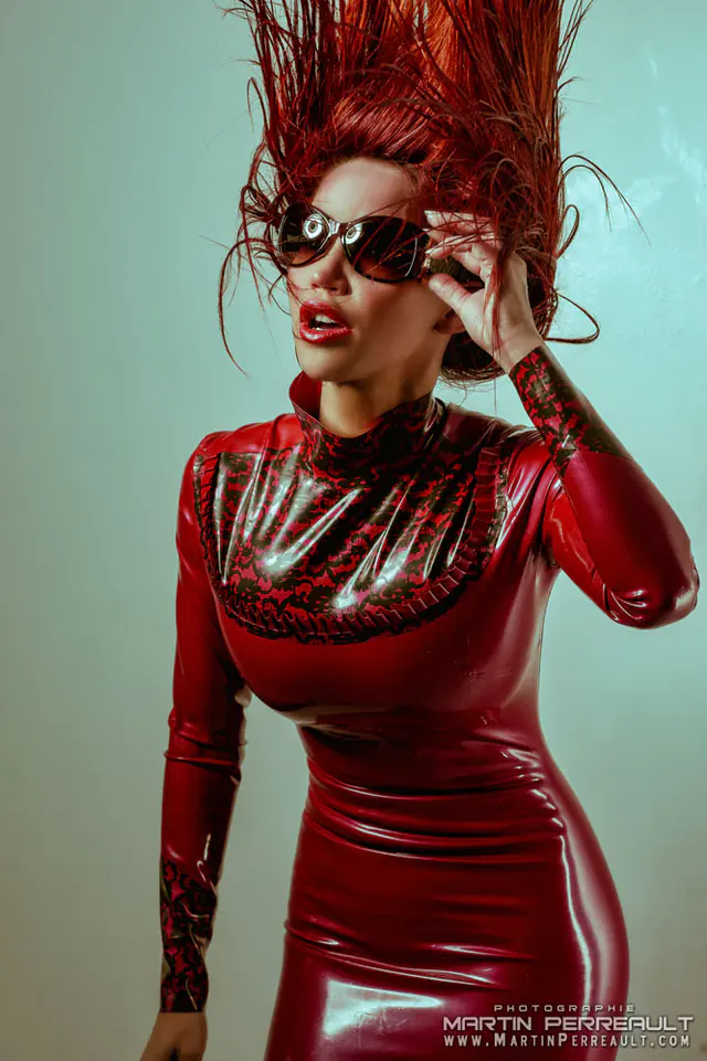 Bianca Beauchamp in a red latex dress and sunglasses, her hair blown upward