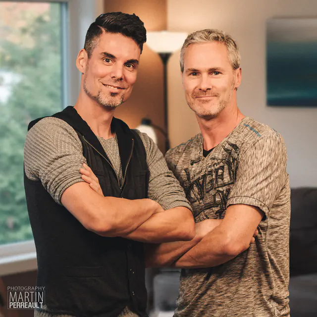 Two men with their arms crossed in a living room
