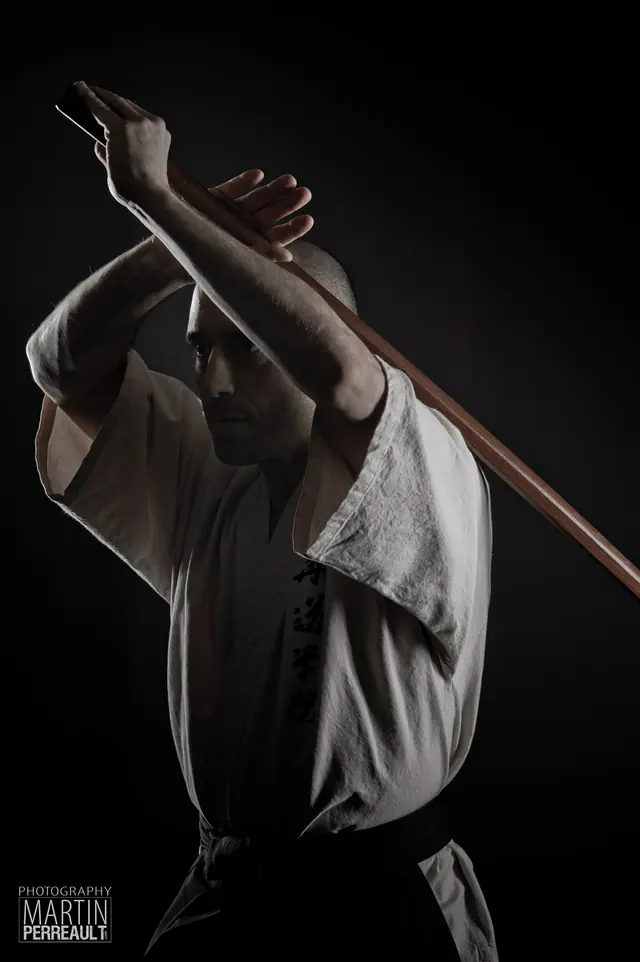 A martial artist raising a wooden staff overhead