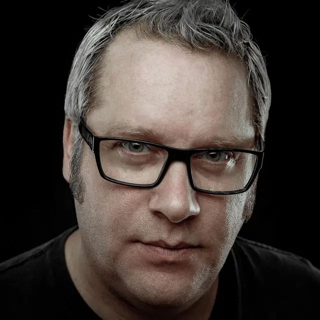 Gil Perron in black glasses, close portrait