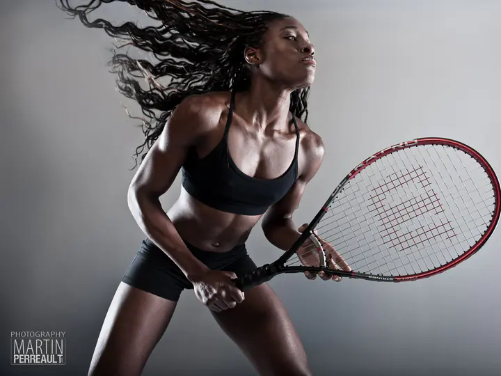 A tennis player swinging a racket, her hair flying