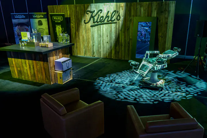 The Kiehl’s stand: a wooden counter, a barber chair and two leather armchairs