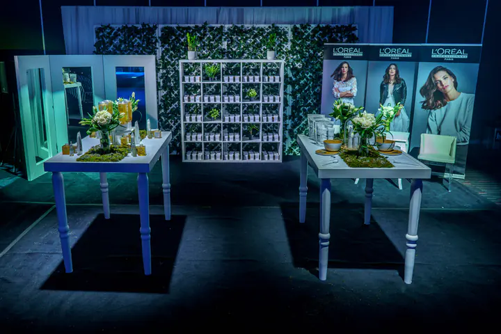 A L’Oréal stand with white tables, shelving and campaign portraits