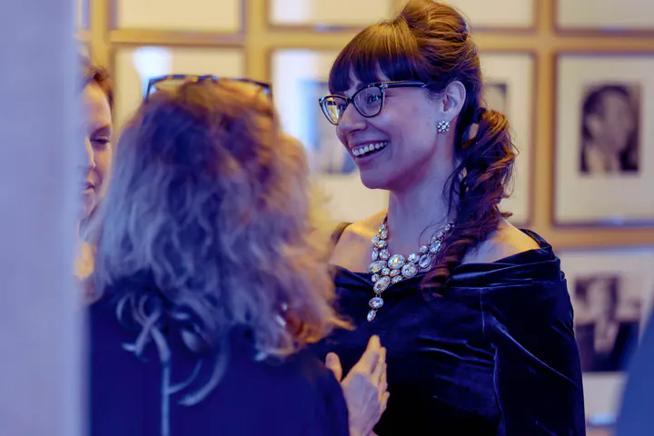 A guest in glasses and a velvet dress, laughing in conversation