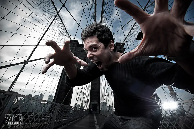 Martin Perreault on the Brooklyn Bridge in New York, lunging at the camera with his hands spread